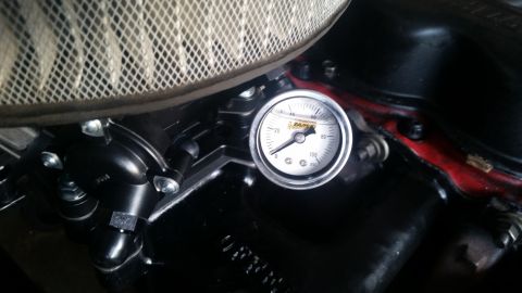 1985 Ford Bronco - A close-up view of a fuel pressure gauge attached to a black carburetor on a vehicle engine. The gauge reads approximately 40 PSI.