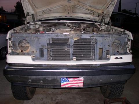 1988 Ford Bronco - The front of a white Ford truck, likely from the late 1980s, is shown with its hood open, revealing the engine compartment and radiator.