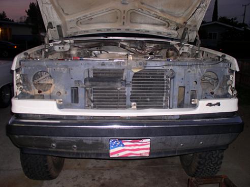 Front of a white Ford truck with hood open, showing the engine bay and grille. Has a "4x4" badge on the fender