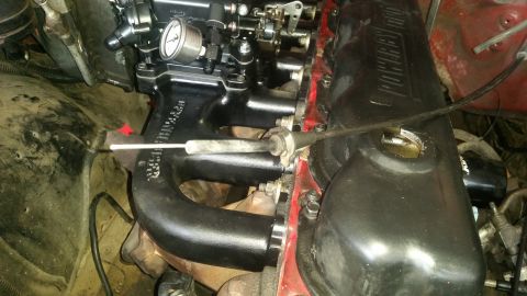 1985 Ford Bronco - A close-up view of the engine bay of a Ford Bronco, focusing on the intake manifold and valve cover. The engine features aftermarket black…
