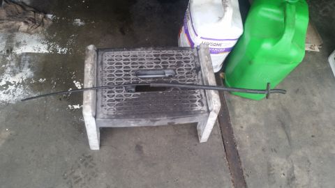 1985 Ford Bronco - A black cable or hose is resting on a plastic step stool. Two large plastic containers, one white and one green, are visible in the backgro…