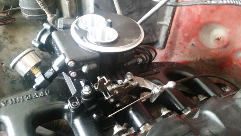 1985 Ford Bronco - A close-up view of a black throttle body assembly mounted on a black intake manifold, with a small pressure gauge attached. The throttle bo…