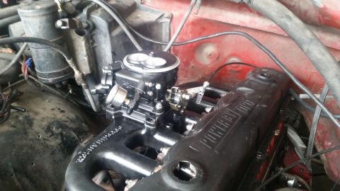 1985 Ford Bronco - A close-up view of a modified engine bay, featuring a black carburetor and intake manifold with "POWER BY FORD" text visible on the valve c…