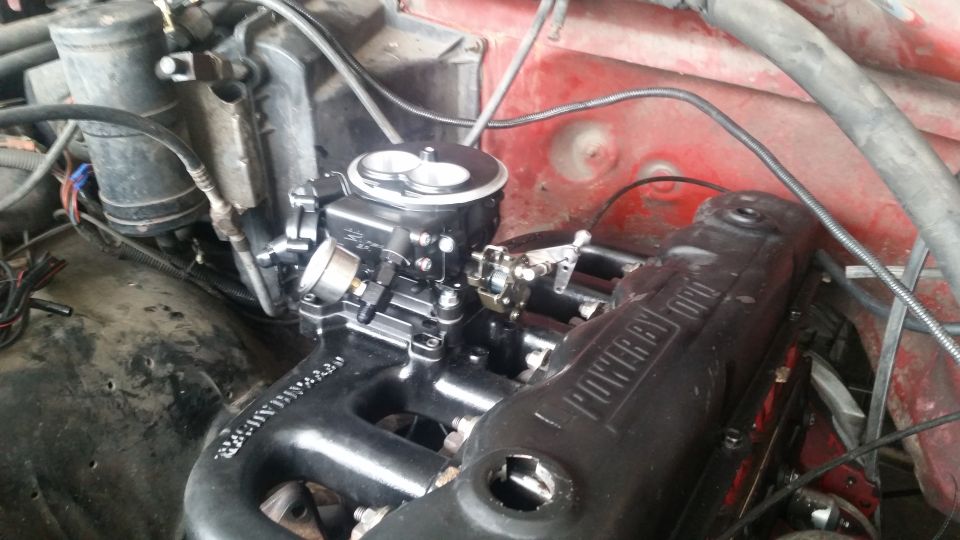 Close-up of a Ford engine with a black carburetor and intake manifold.