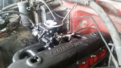1985 Ford Bronco - A close-up view of a Ford engine bay, featuring a black "POWER BY FORD" valve cover and a black carburetor.