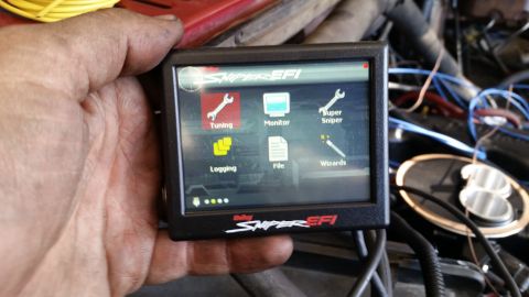1985 Ford Bronco - A hand holds a Holley Sniper EFI digital display showing the main menu with options for Tuning, Monitor, Super Sniper, Logging, File, and W…