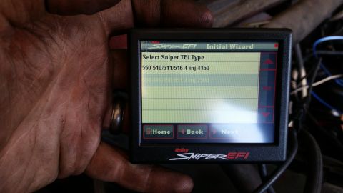 1985 Ford Bronco - A hand holding a Holley Sniper EFI digital display screen showing an initial wizard setup for selecting a Sniper TBI type. The screen displ…