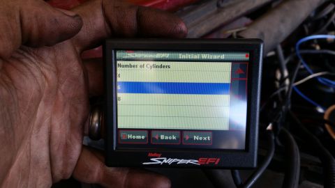 1985 Ford Bronco - A hand holds a Holley Sniper EFI digital display showing an initial wizard setup screen for selecting the number of cylinders, with '6' hig…