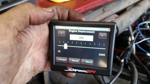 1985 Ford Bronco - A hand holds a Holley Sniper EFI digital display showing an engine displacement setting of 305. The screen is part of an engine bay with vi…