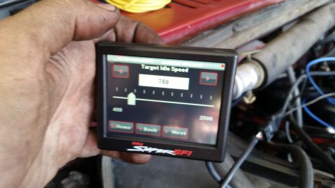 1985 Ford Bronco - A hand holds a Holley Super EFI digital display showing a target idle speed of 750 RPM, with engine components visible in the background.