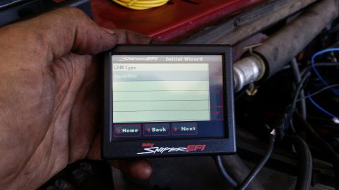 1985 Ford Bronco - A hand holds a Holley Sniper EFI digital display showing an initial wizard screen for "CAM Type" with "Stock/Mild" selected. The display is…