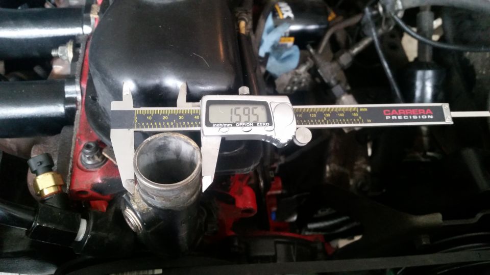 Digital caliper measuring a pipe at 15.95 mm in an engine bay.