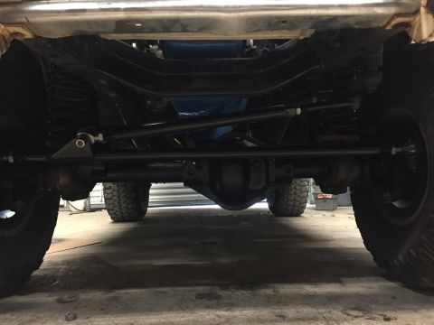 1969 Ford Bronco - The underside of a vehicle shows the front axle, steering components, and suspension with large tires visible on either side. The vehicle a…