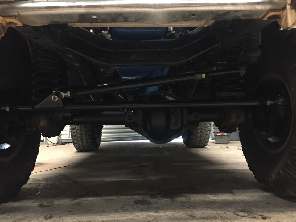 Underside of a 1969 Ford Bronco showing front axle, steering, suspension, and tires.