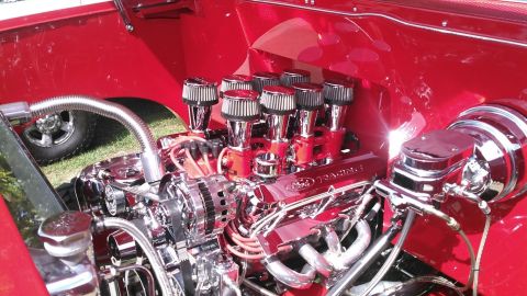 1992 Ford Bronco - A highly polished chrome engine with eight individual air intake filters is visible in the engine bay of a red vehicle. The engine features…