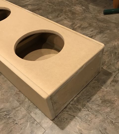 1995 Ford Bronco - A tan wooden box with two circular cutouts is shown on a tiled floor. The box appears to be a custom-made enclosure, possibly for speakers.