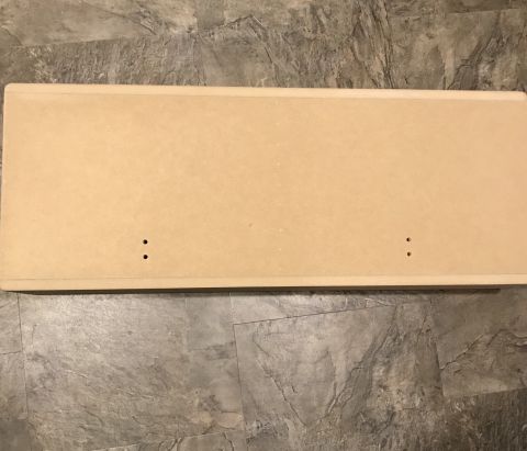1995 Ford Bronco - A light brown, rectangular wooden board with two pairs of small holes drilled into it is shown lying on a gray tiled floor.
