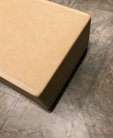 1995 Ford Bronco - A close-up view of a light brown, rectangular object with rounded edges resting on a grey tiled floor.