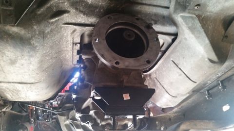 1985 Ford Bronco - The underside of a vehicle shows a transmission with a new black transmission mount attached. A large circular flange with bolt holes is vi…