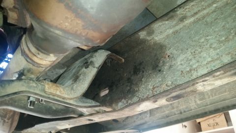 1985 Ford Bronco - This is a close-up, low-angle shot of the underside of a vehicle, focusing on the exhaust system and frame components. The frame appears to…