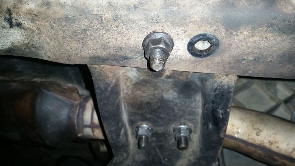 Close-up of vehicle undercarriage showing bolts, nuts, and a metal bracket.