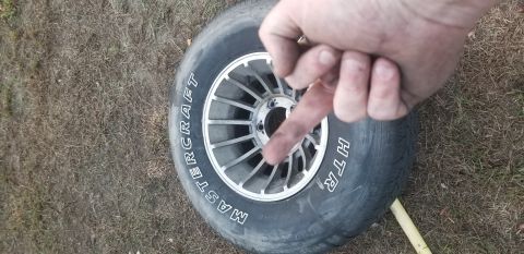 1995 Ford Bronco - A close-up view of a tire with the brand name "MASTERCRAFT" and "HTR" visible. A person's dirty hand is pointing towards the center of the…