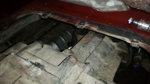 1985 Ford Bronco - A close-up view of a vehicle's transmission and transfer case, showing various metal components with some grease and orange markings. A sil…