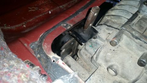 1985 Ford Bronco - A close-up view of a transmission mount and part of a transmission housing in a vehicle. The transmission mount is black metal with a rubbe…
