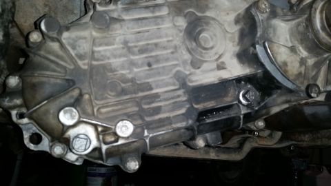 1985 Ford Bronco - This is a close-up view of the underside of a vehicle's transmission casing. The metal casing is dirty and shows signs of oil leakage aroun…