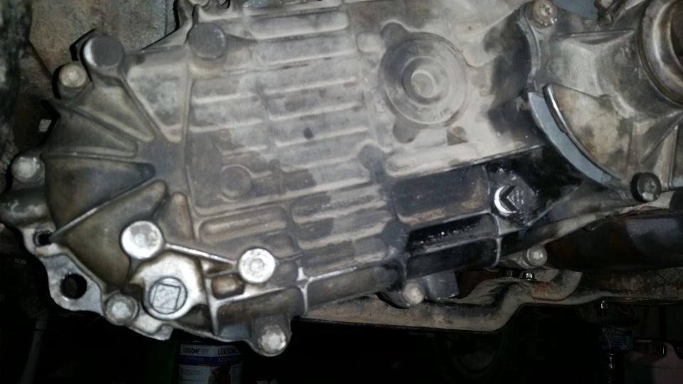 Underside of a dirty vehicle transmission casing with oil leaks.