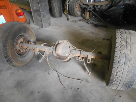 1992 Ford Bronco - A rear axle assembly with two tires attached is shown in a garage setting. The axle is rusty and appears to be from an older vehicle.
