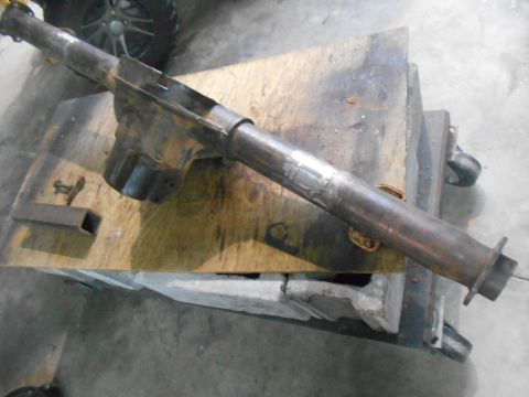 1992 Ford Bronco - A rusty metal exhaust pipe assembly is resting on a wooden workbench. The pipe has a complex shape with a larger housing section and a smal…