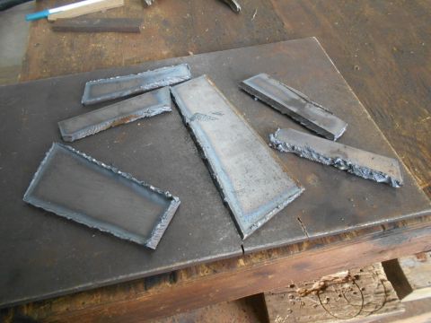 1992 Ford Bronco - Several rectangular metal pieces with rough, cut edges are arranged on a dark metal surface. The metal pieces appear to be remnants from a…