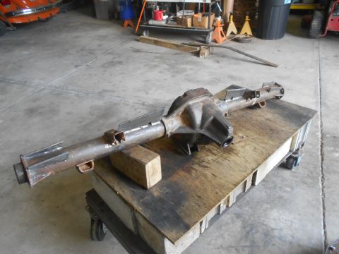1992 Ford Bronco - A rusty Ford Bronco rear axle assembly is mounted on a wooden cart in a garage setting. The assembly features a differential housing and tw…