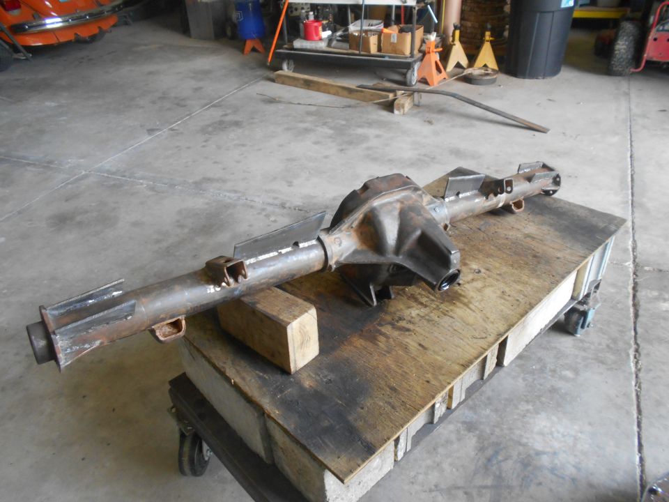 Rusty Ford Bronco rear axle assembly on a wooden cart.