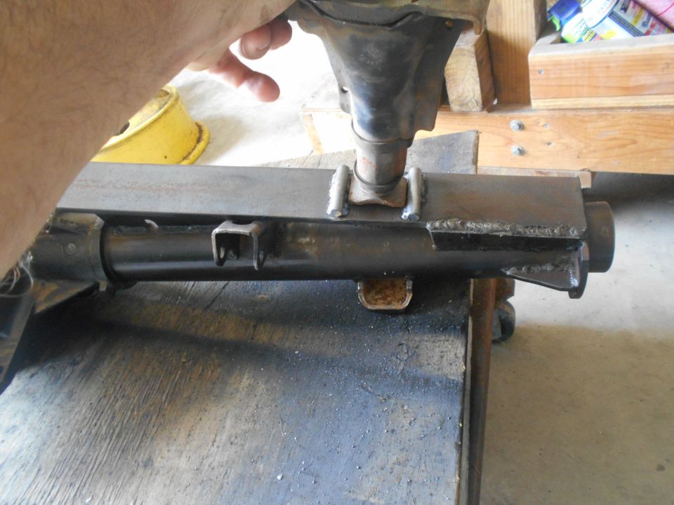 Close-up of a welded metal automotive part being held by a hand.