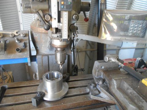 1992 Ford Bronco - A close-up view of a milling machine with a drill bit and a metal workpiece clamped to the table. A digital readout display is visible in t…