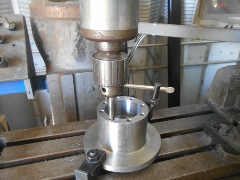 1992 Ford Bronco - A close-up view of a metal part being machined on a milling machine. The part has several holes around its perimeter and a threaded hole in…