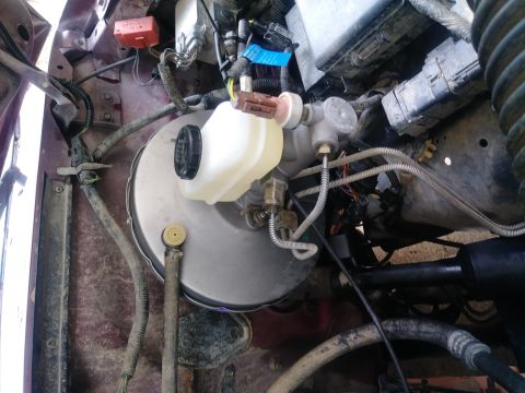 1996 Ford Bronco - The engine bay of a 1996 Ford Bronco shows the brake master cylinder and reservoir, along with various hoses and electrical connectors.