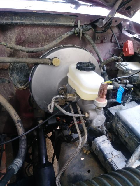 1996 Ford Bronco - The image shows a close-up view of the brake master cylinder and brake booster assembly in an engine bay. Various hoses, wires, and electri…