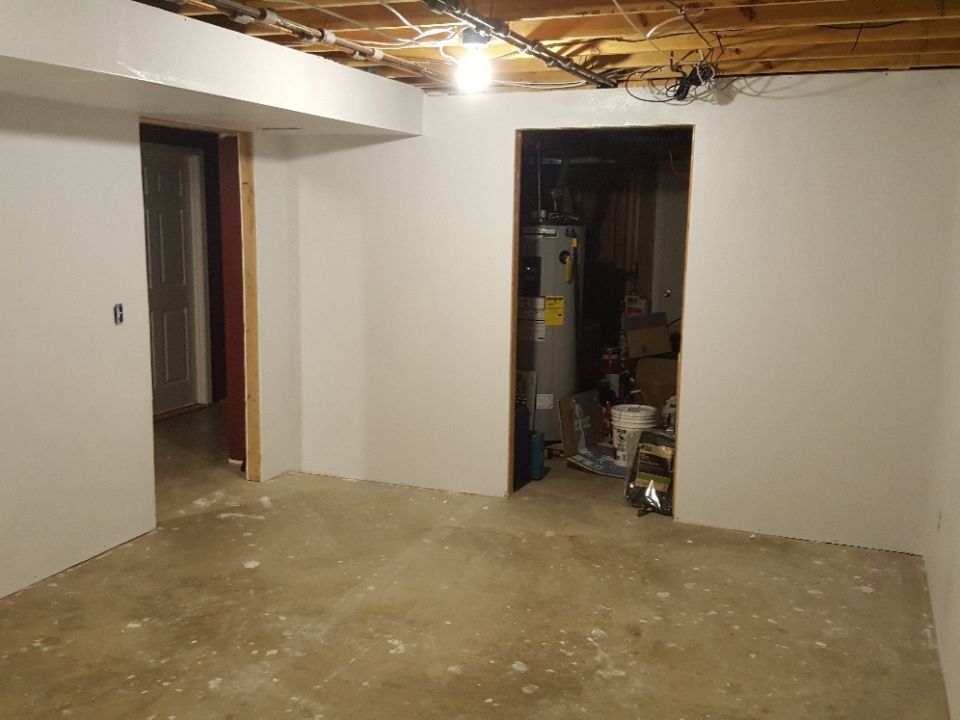 Unfinished basement with drywall, exposed ceiling, and a water heater.