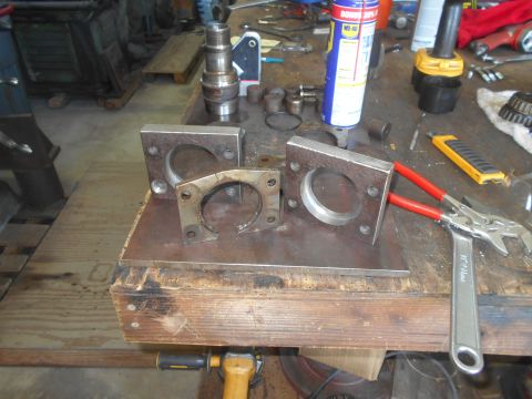 1992 Ford Bronco - A workbench is covered with tools and metal parts. Visible items include a can of WD-40, a utility knife, a wrench, and several metal brack…