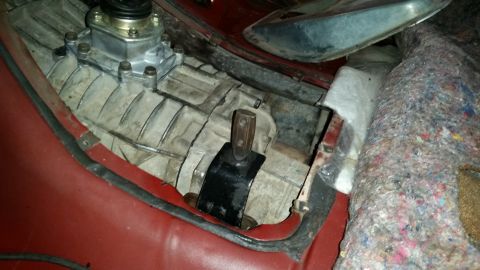 1985 Ford Bronco - A close-up view of a vehicle's transmission tunnel and shifter assembly, showing the metal transmission casing, a black shifter boot, and s…