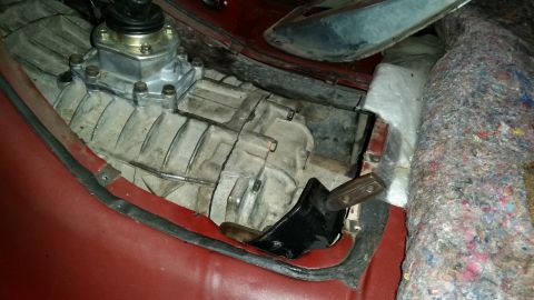1985 Ford Bronco - A close-up view of a manual transmission shifter and gearbox assembly in a vehicle with a red interior. The transmission housing is made of…