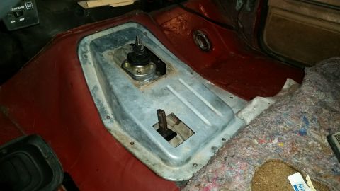 1985 Ford Bronco - The interior of a vehicle shows a removed center console with exposed floor and transmission tunnel. A manual shifter assembly is visible,…