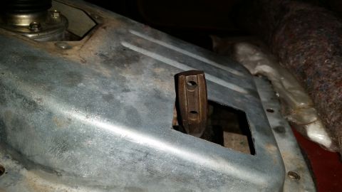 1985 Ford Bronco - A close-up view of a metal component with a hexagonal, brown metal lever protruding through a rectangular cutout. The metal appears to be p…