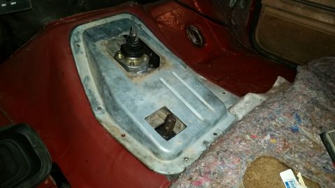 1985 Ford Bronco - The interior of a vehicle shows the transmission tunnel with the shifter and a hole for the transfer case lever. The carpeting is removed.