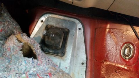 1985 Ford Bronco - The interior of a vehicle shows the transmission tunnel area with the shifter boot exposed.