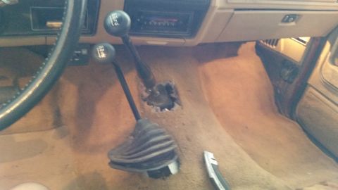 1985 Ford Bronco - This image shows the interior of a vehicle, focusing on the dual shifters and the carpeted floor.