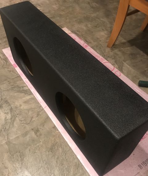 1995 Ford Bronco - A black dual subwoofer enclosure with two circular openings rests on a pink mat.